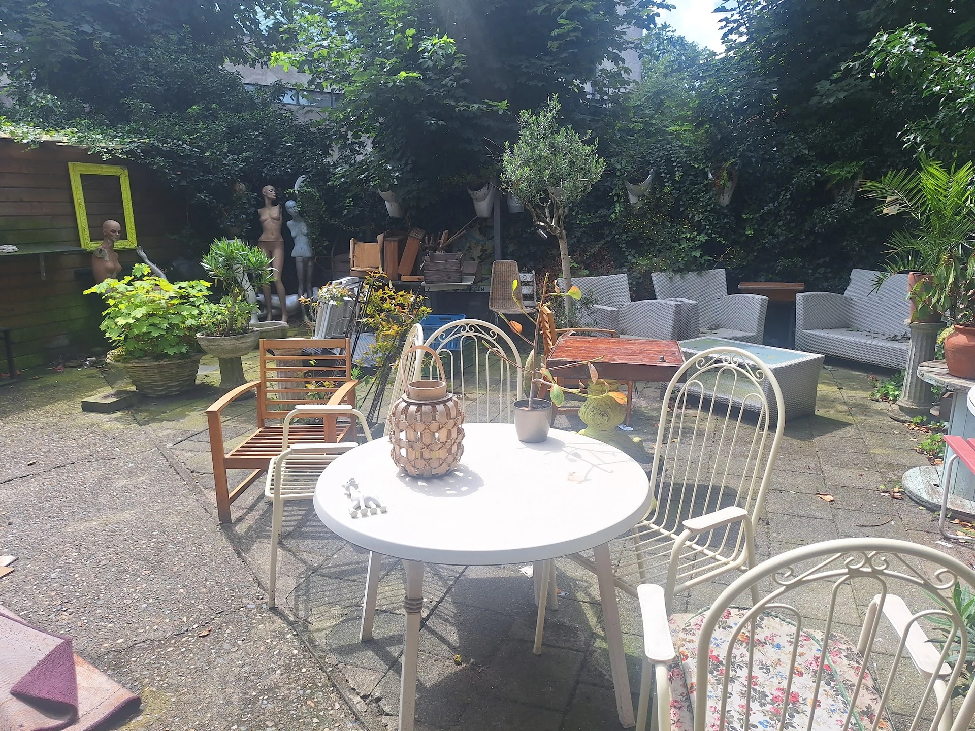 Terras met ronde tafel en stoelen tussen groen, met mand en decoratie op tafel