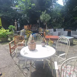 Terras met ronde tafel en stoelen tussen groen, met mand en decoratie op tafel