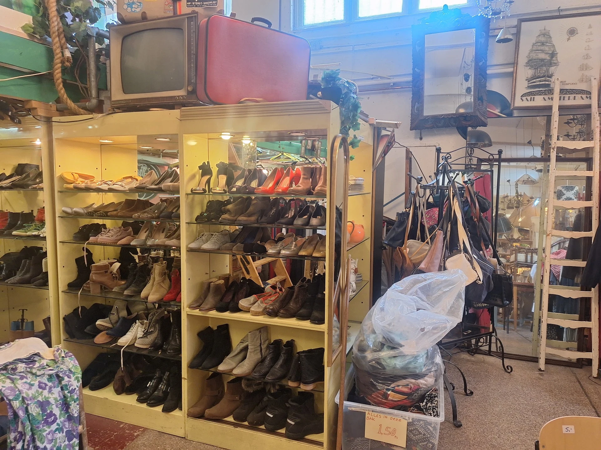 Overzicht van kringloopwinkel met schoenenkast, fietsen, vintage televisie en diverse tweedehands spullen