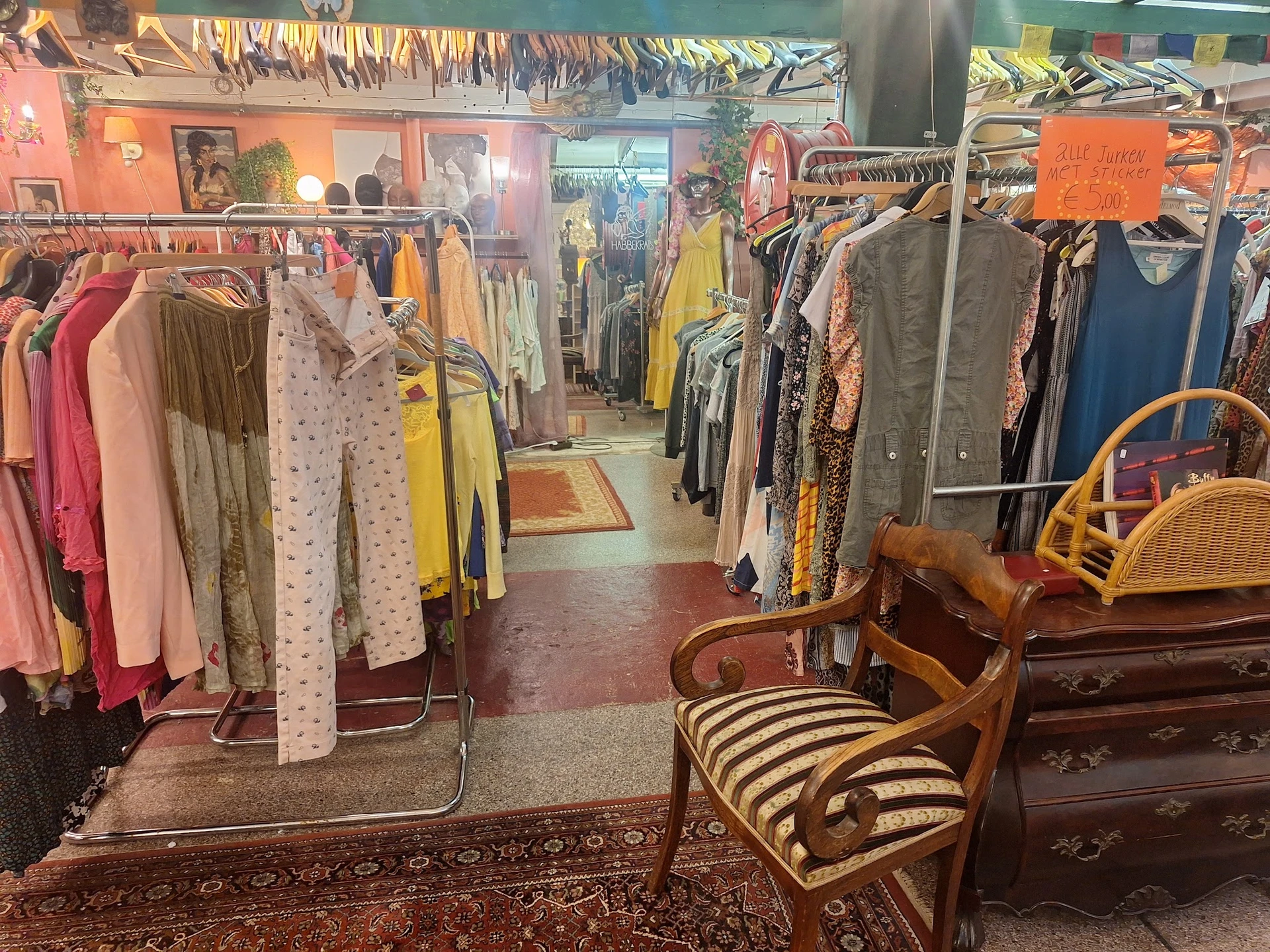 Interieur van kringloopwinkel met kledingrekken, vintage meubels en diverse tweedehands artikelen