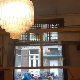 Winkelbinnenkant met glazen voorzijde, moderne hanglamp, houten balustrade en zicht naar straat met voorbijgangers