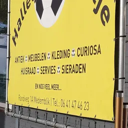 Geel bord met tekst over aanbod en contactgegevens van kringloopwinkel