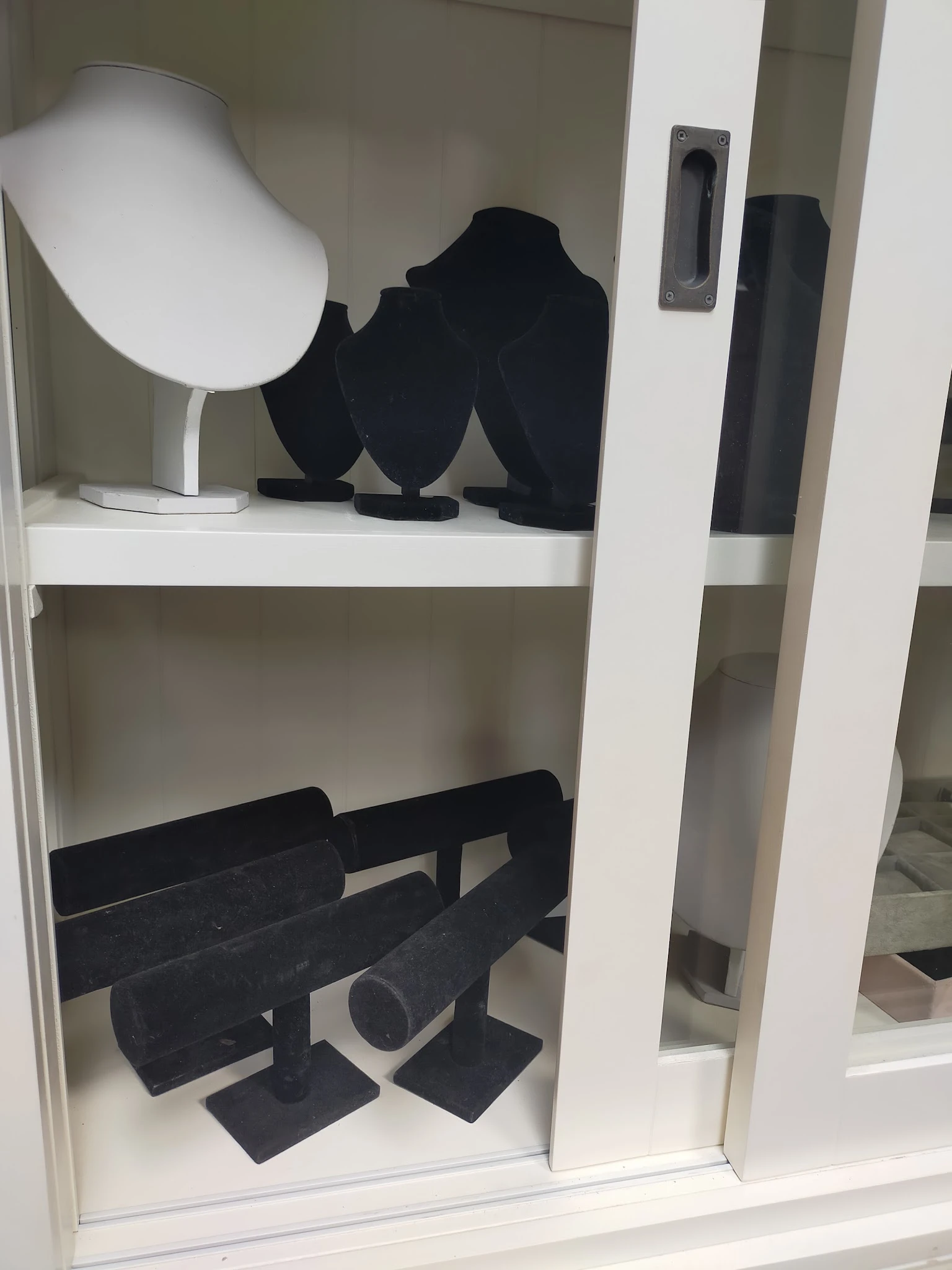 Witte stellingkast met zwarte kleding en accessoires uitgestald op verschillende niveaus