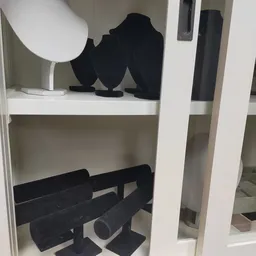 Witte stellingkast met zwarte kleding en accessoires uitgestald op verschillende niveaus