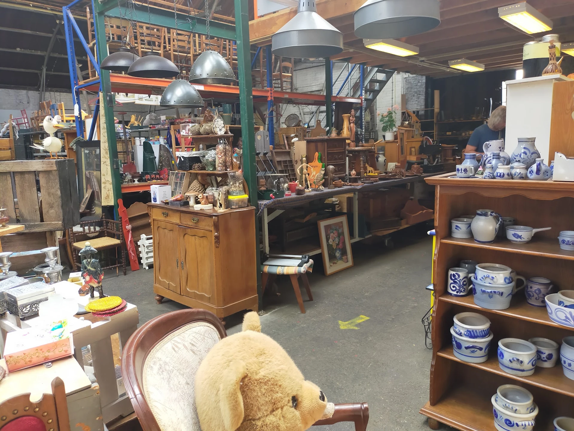 Winkelvloer met houten meubels, hanglampjes, stellingen en diverse tweedehands spullen in een brocantebedrijf