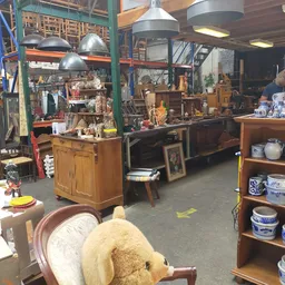 Winkelvloer met houten meubels, hanglampjes, stellingen en diverse tweedehands spullen in een brocantebedrijf