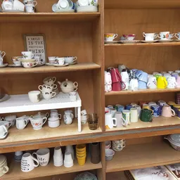 Houten kasten met servies, huishoudspullen en diverse kleine artikelen op elkaar gestapeld
