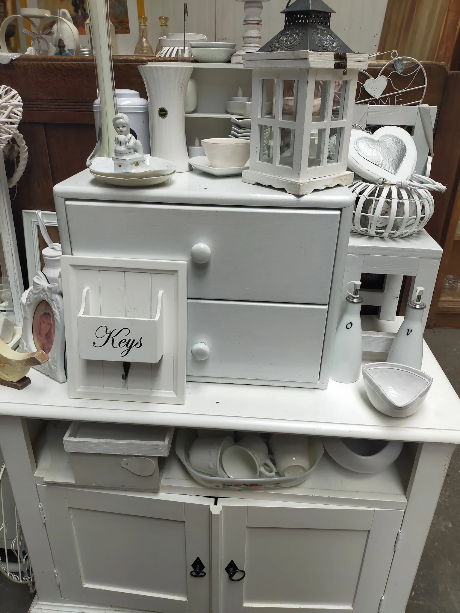Witte huishoudelijke items en decoratie: organizer met sleutelhouder, laden, schaaltje en decoratieve accessoires op display.