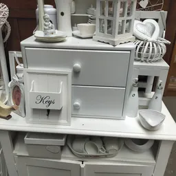 Witte huishoudelijke items en decoratie: organizer met sleutelhouder, laden, schaaltje en decoratieve accessoires op display.