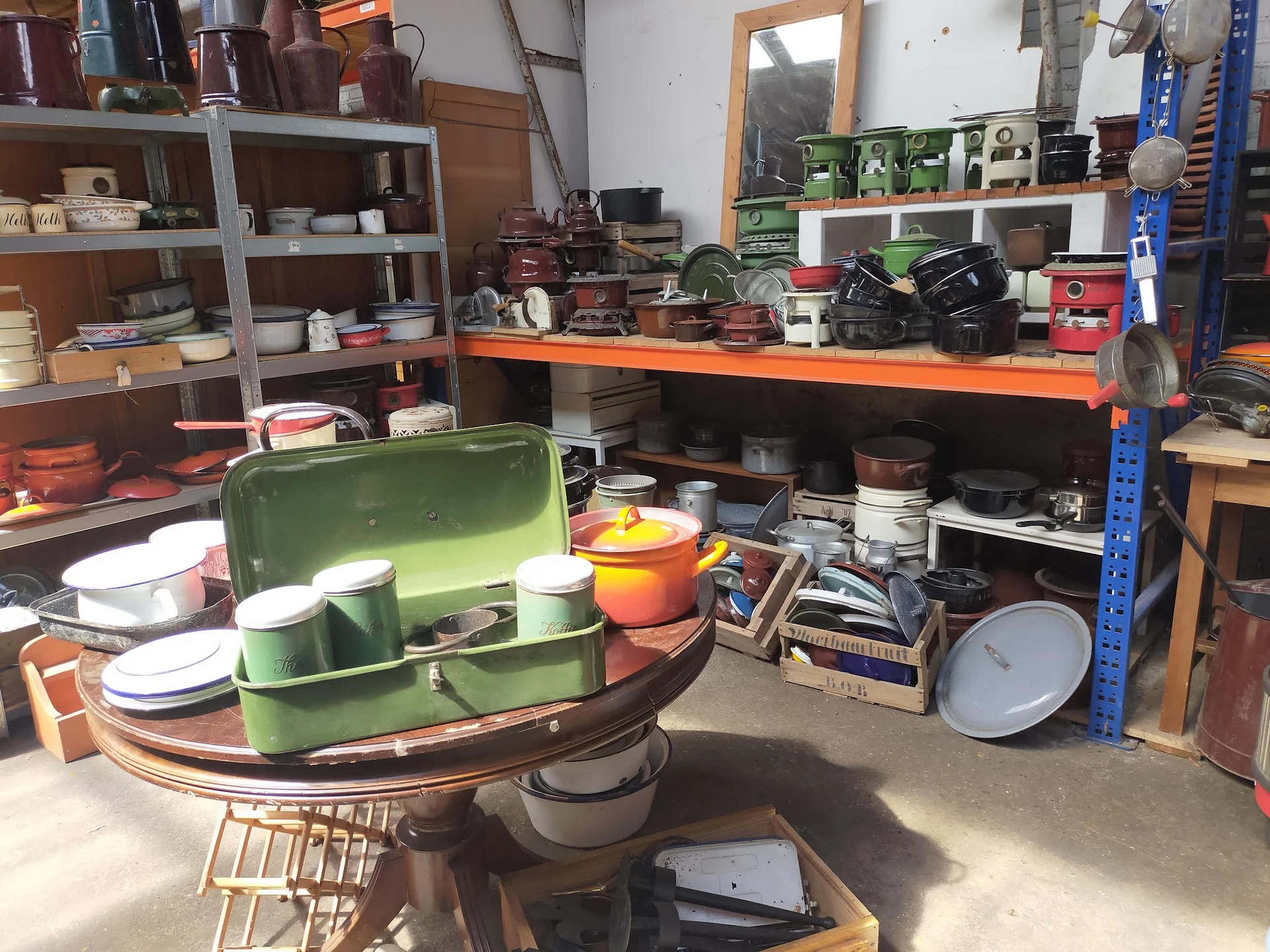 Brocanterie interieur met verzameling huishoudelijke spullen, servies, pannen en decoratieartikelen op tafels en stellingen