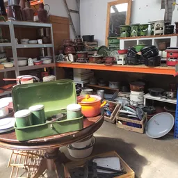 Brocanterie interieur met verzameling huishoudelijke spullen, servies, pannen en decoratieartikelen op tafels en stellingen
