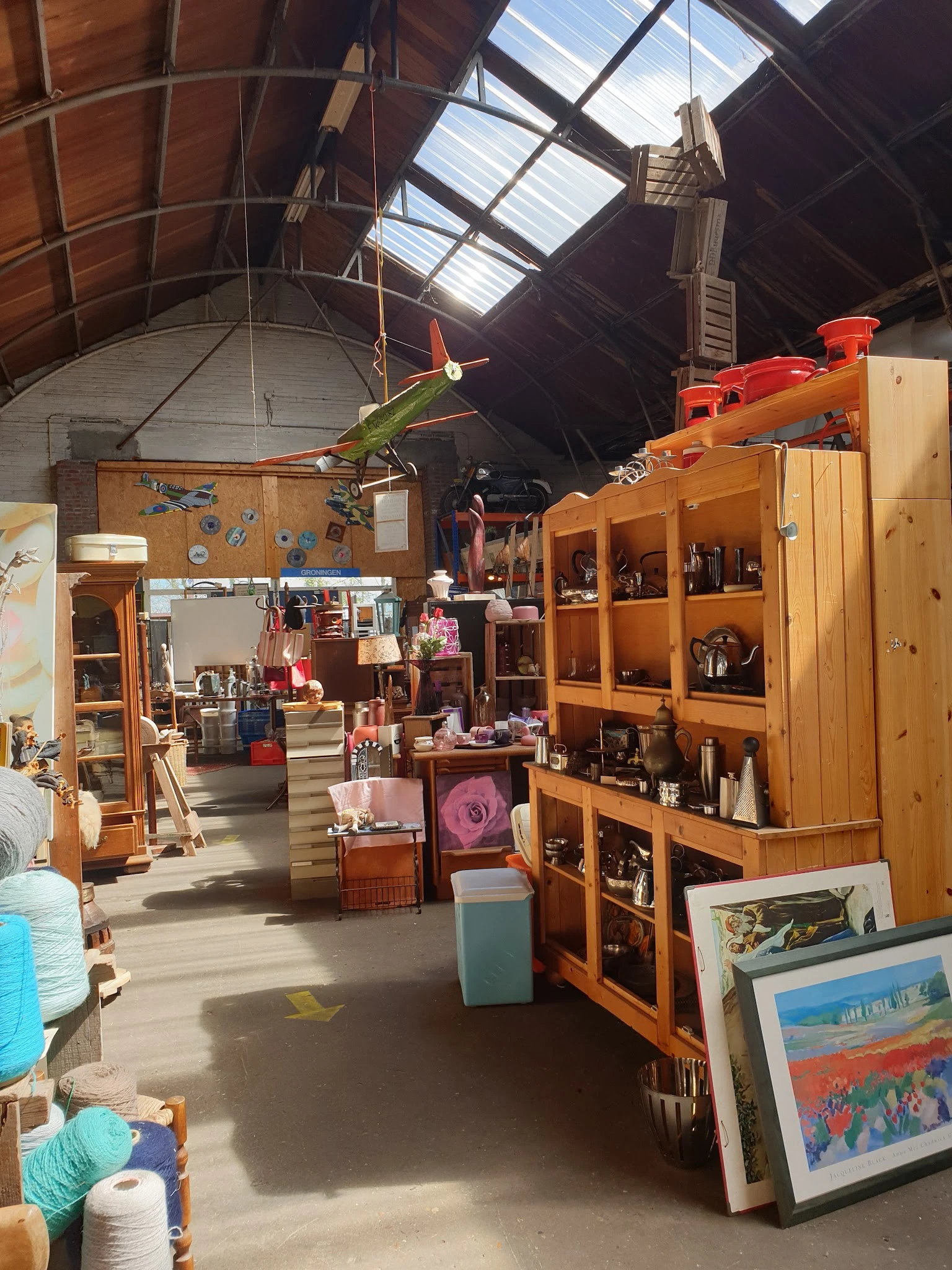 Winkelvloer met houten kasten, stellingen, vintage spullen en decoraties verspreid door de ruimte
