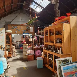 Winkelvloer met houten kasten, stellingen, vintage spullen en decoraties verspreid door de ruimte