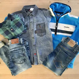 Uitgestalde tweedehands kleding: geruit overhemd, blauwe hoodie, jeans en geruit jasje op houten vloer