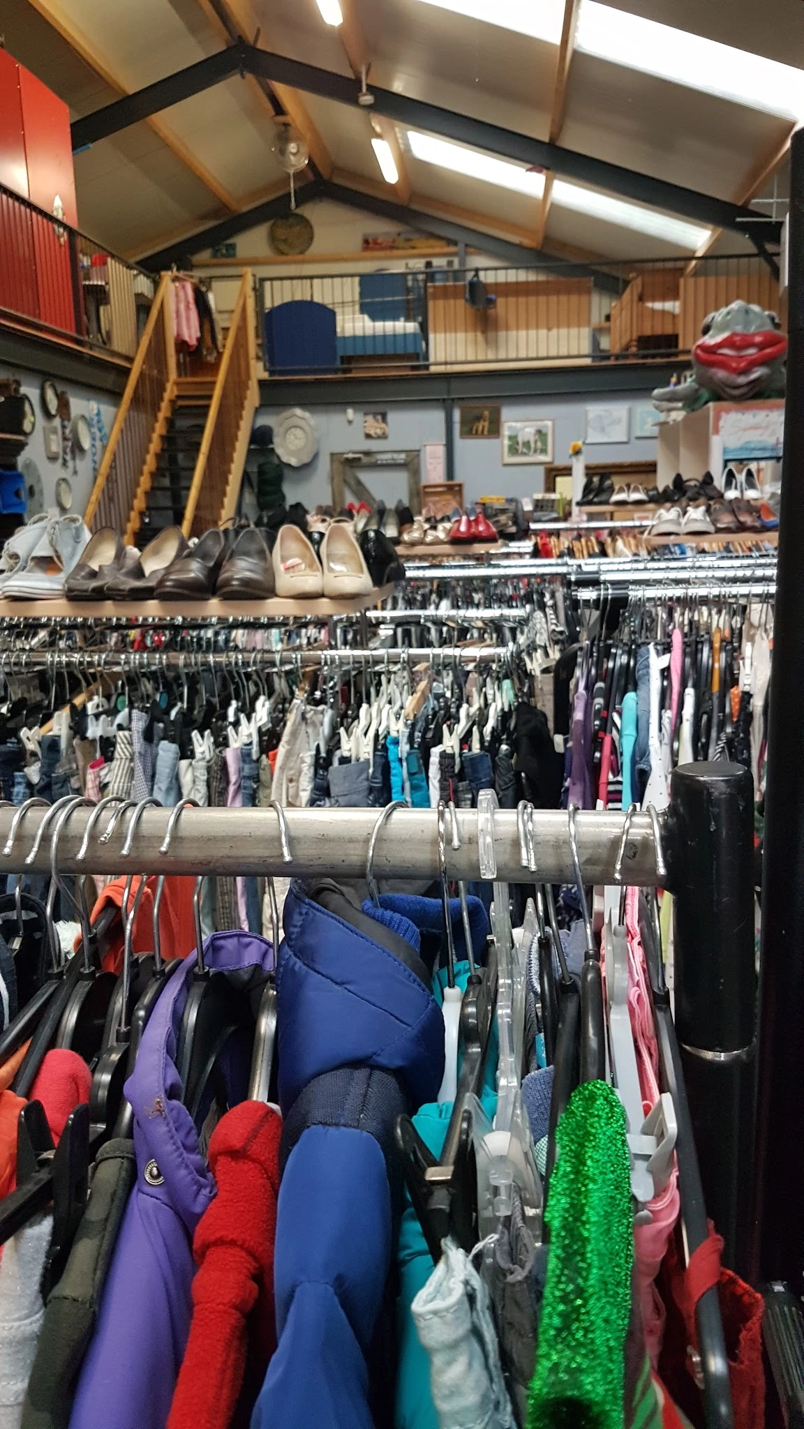 Rekken met tweedehands kleding en schoenen uitgestald in een kringloopwinkel