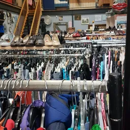 Rekken met tweedehands kleding en schoenen uitgestald in een kringloopwinkel