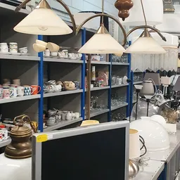 Stellingen vol serviesgoed, glazen en huishoudartikelen in een kringloopwinkel