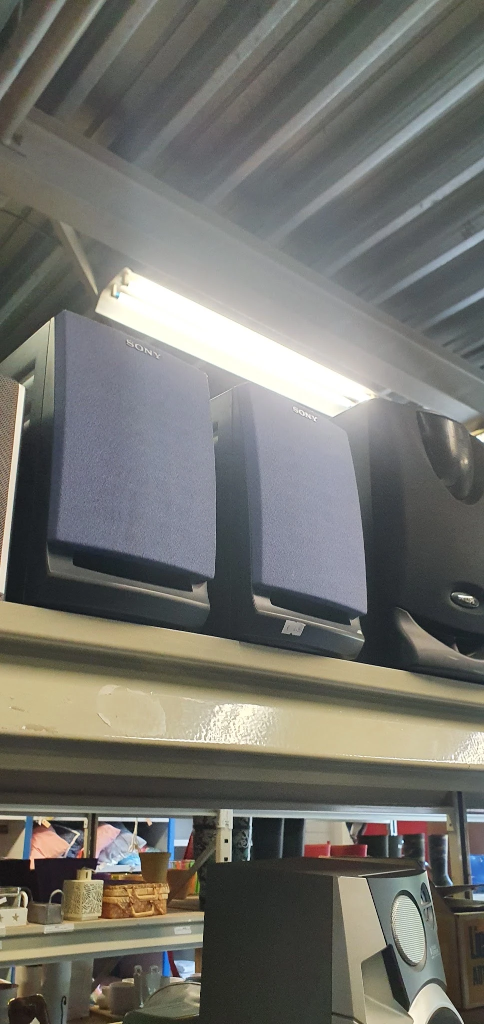 Drie zwarte Sony luidsprekers op een plank tegen een witte muur