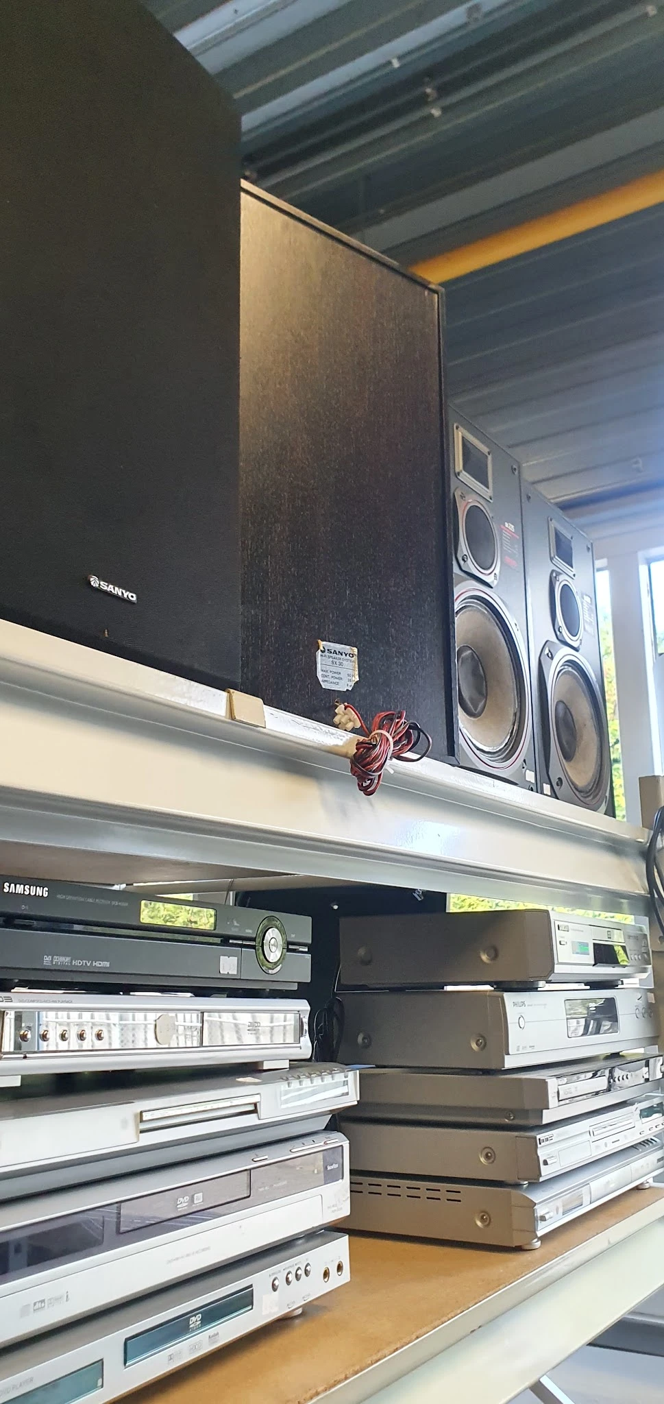 Zwarte luidsprekers en versterker op een plank in de winkel, met rood snoer