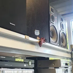 Zwarte luidsprekers en versterker op een plank in de winkel, met rood snoer