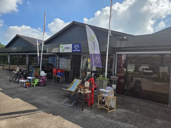 Voorgevel van kringloopwinkel Hebbes met uitgestalde spullen op het terras, fietsen en speelgoed zichtbaar