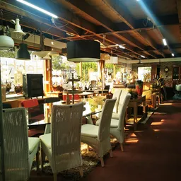 Ruim kringloopwinkelinterieur met eettafels, stoelen, lampen en diverse meubels en inrichtingsspullen
