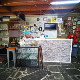 Binnenaanzicht van kringloopwinkel met toonbank, klokken aan de muur, stellingen met spullen en decoratieve items