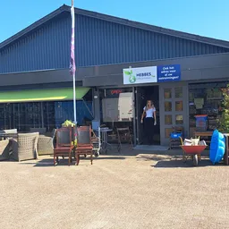 Voorgevel van kringloopwinkel Hebbes met ingang, winkelnaam zichtbaar, uitgestalde spullen op het terras en een medewerker in