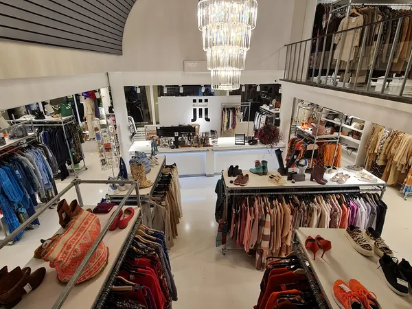 Overzicht van de winkelvloer met kledingrekken, schoenen en accessoires uitgestald