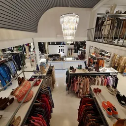 Overzicht van de winkelvloer met kledingrekken, schoenen en accessoires op verschillende niveaus