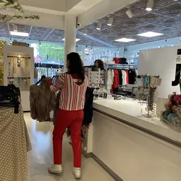 Winkelinterieur met kledingrekken, toonbanken en klanten die door de winkel lopen