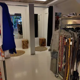 Winkelinterieur met kledingrekken, houten zuilen en uitgestalde kleding
