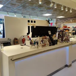 Winkelinterieur met witte toonbank, zwart logo, uitgestalde artikelen en bakstenen muur