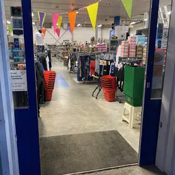 Winkelvloer van kringloopwinkel met kledingrekken, rode kratten en dozen met artikelen
