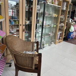 Winkelvloer met rieten stoel en glazen vitrinekasten met servies en huishoudartikelen