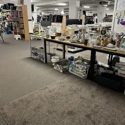 Tafel met glazen, servies en decoratieve huishoudartikelen uitgestald in kringloopwinkel