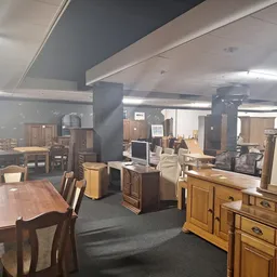 Ruim interieur van kringloopwinkel met diverse meubels, tafels, kasten en huishoudelijke artikelen uitgestald