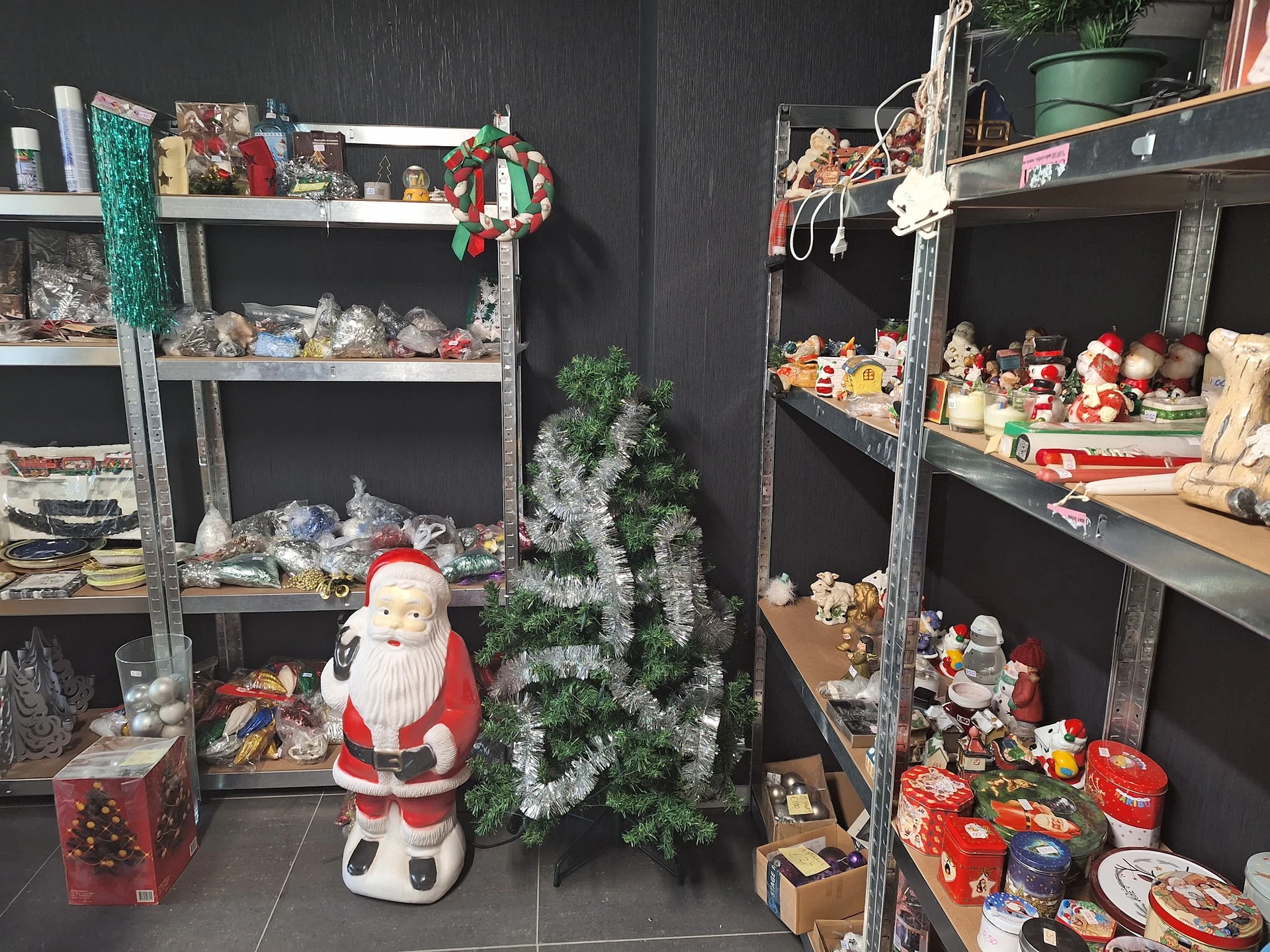 Stellingen met kerstdecoraties en winterartikelen, waaronder Kerstman-figuur, kerstbomen en diverse versiering
