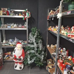 Stellingen met kerstdecoraties en winterartikelen, waaronder Kerstman-figuur, kerstbomen en diverse versiering