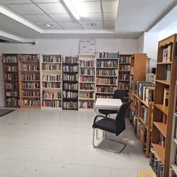 Boekenrekken langs de wanden van een ruime kringloopwinkel met een lichte vloer en zitgelegenheid