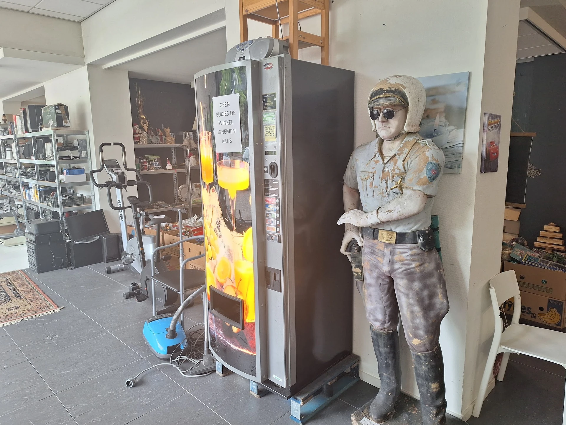 Winkelbinnenruimte met snackautomaatje, kartonnen figuur en diverse items op stellingen