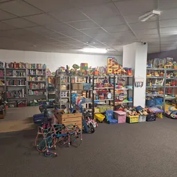 Winkelvloer met boekenkasten, speelgoed, kinderartikelen en diverse spullen in containers en op stellingen