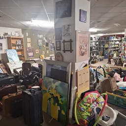 Rommelige winkelvloer met diverse spullen, kleding, meubels en kunstwerken aan muren