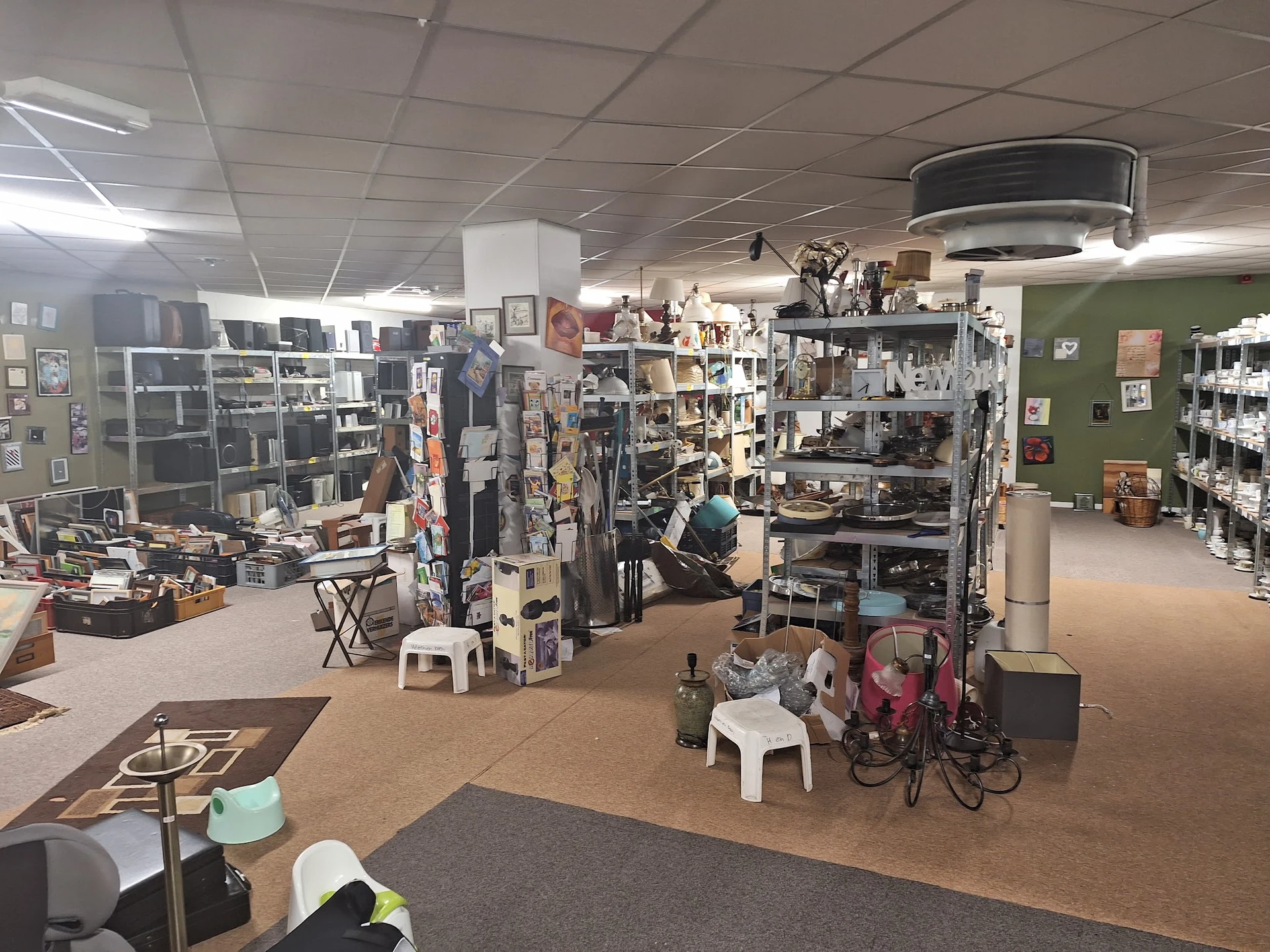 Winkelvloer van kringloopwinkel met stellingen, rekken met kleding, boekenkasten en diverse artikelen uitgestald