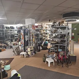 Winkelvloer van kringloopwinkel met stellingen, rekken met kleding, boekenkasten en diverse artikelen uitgestald