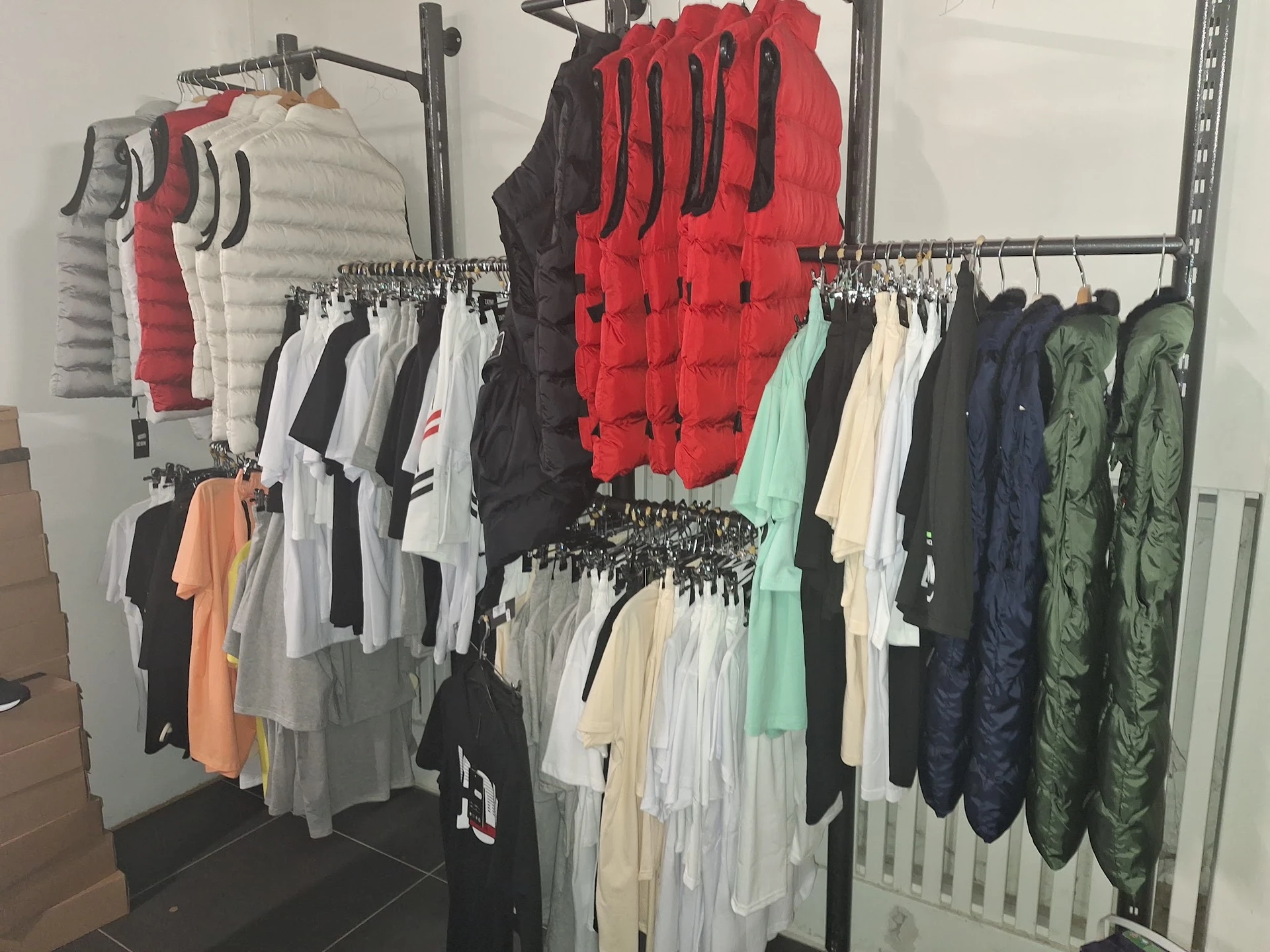 Rekken met tweedehands kleding in verschillende kleuren en soorten, waaronder jassen, truien en t-shirts