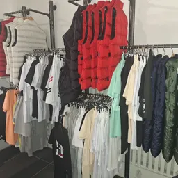 Rekken met tweedehands kleding in verschillende kleuren en soorten, waaronder jassen, truien en t-shirts
