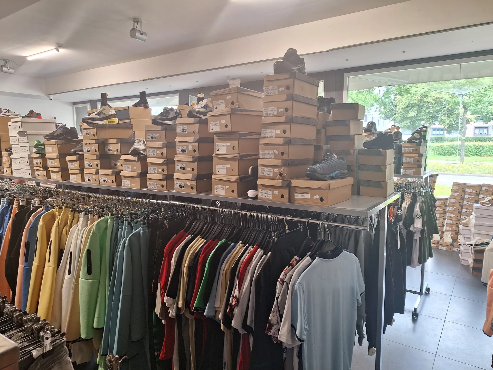 Winkelvloer met rekken tweedehands kleding en grote stapel dozen op displays