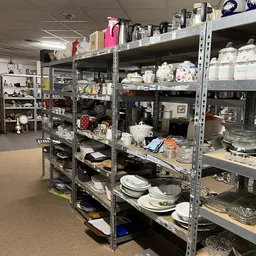 Metalen stellingen met serviesgoed, borden, schalen en keukengerei in een kringloopwinkel