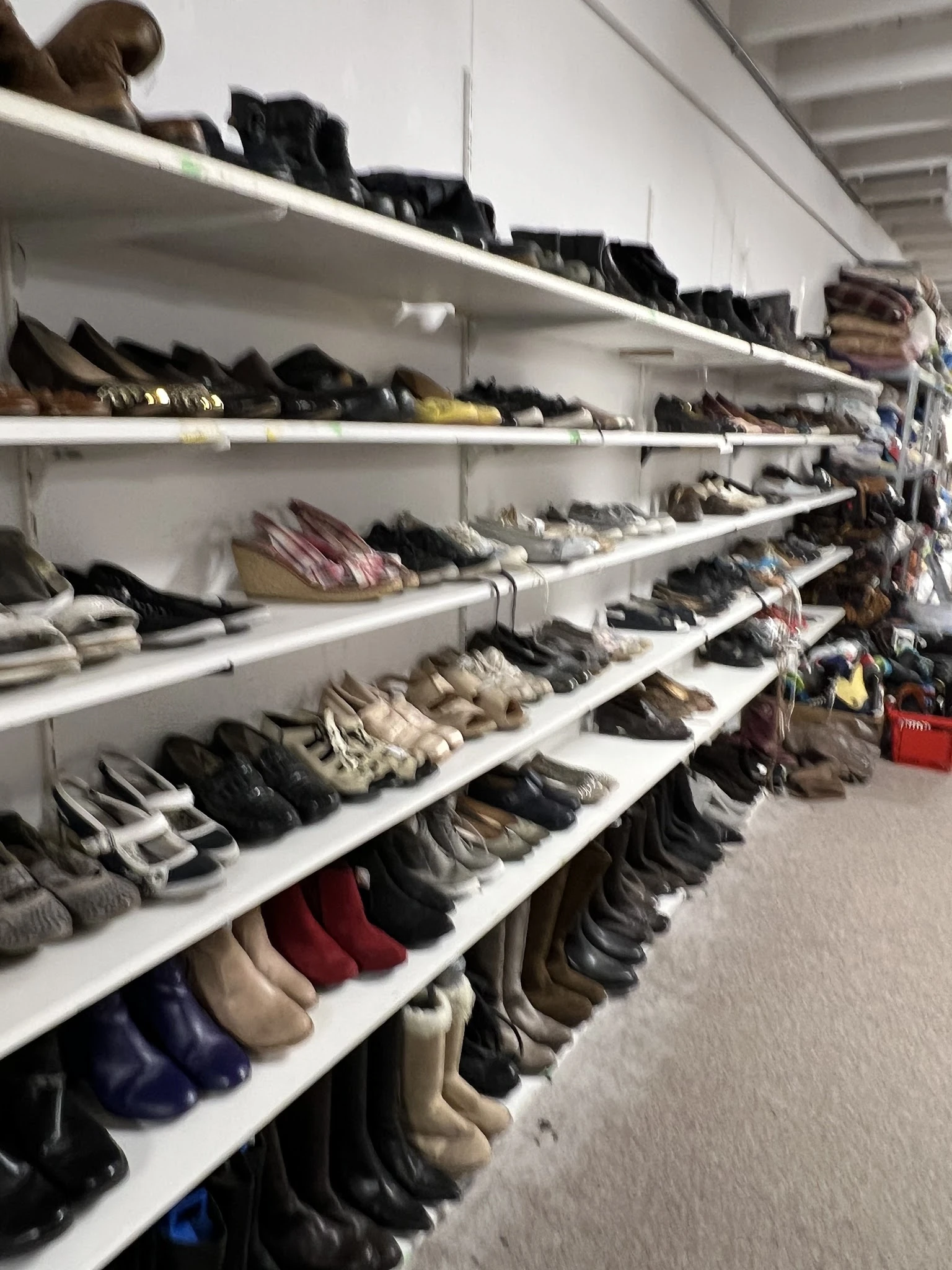 Witte stellingen vol met tweedehands schoenen en laarzen in verschillende kleuren en stijlen